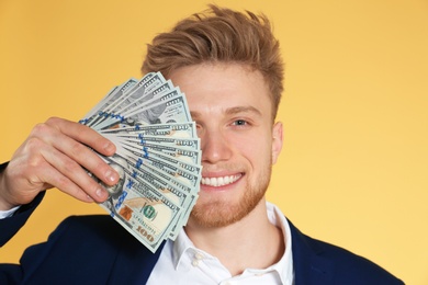 Young businessman with money on color background