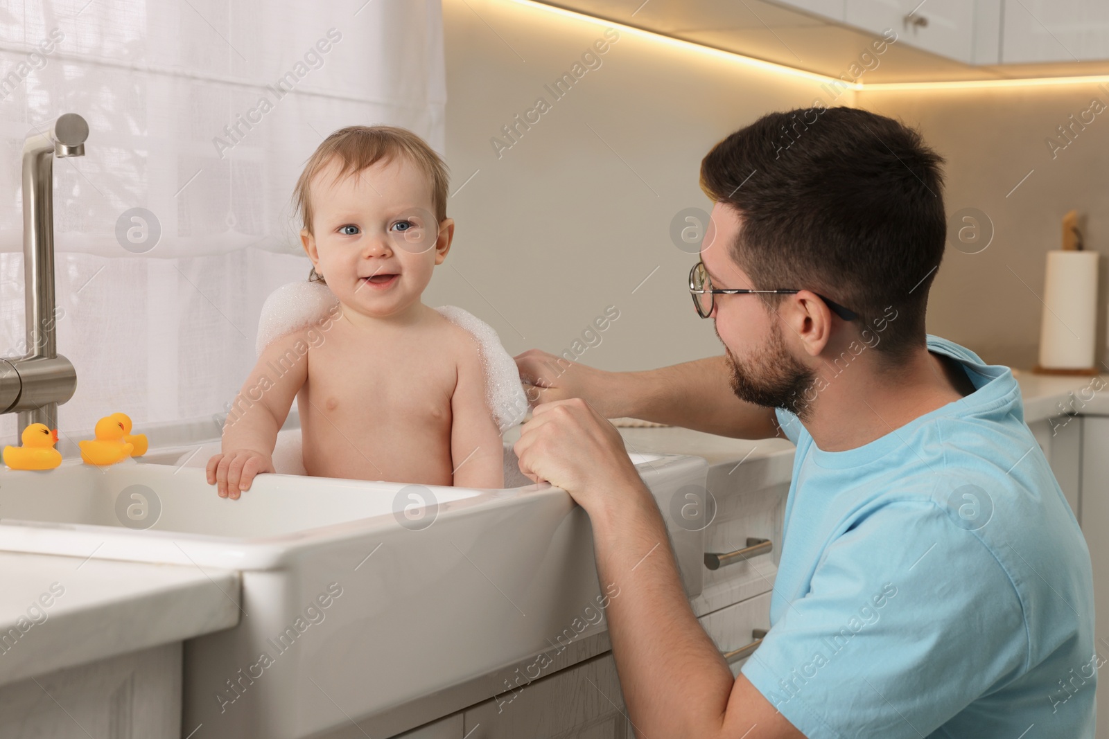 Photo of Father washing his little baby in sink at home