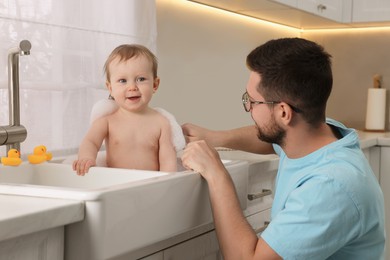 Photo of Father washing his little baby in sink at home