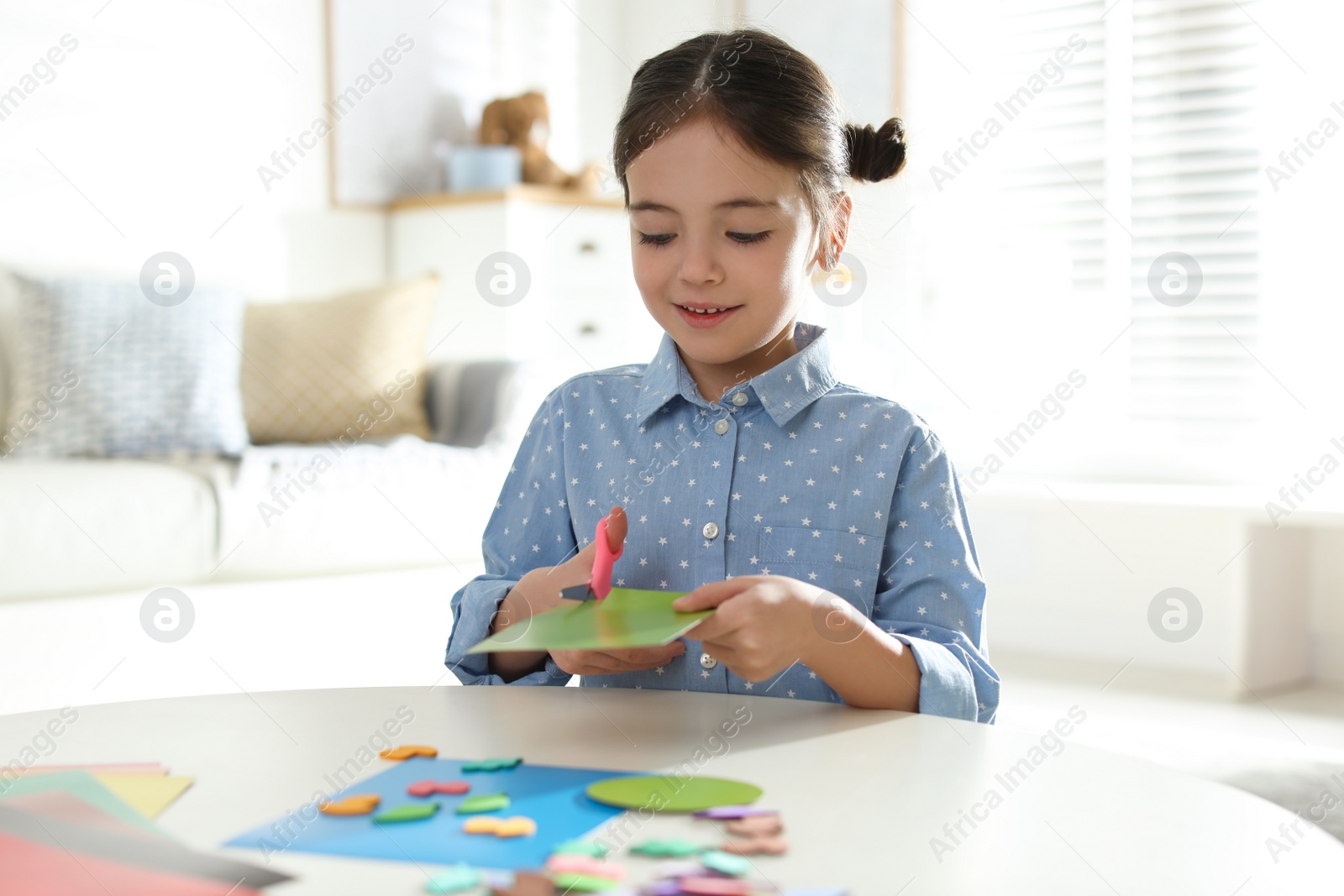 Photo of Little girl making greeting card at table indoors. Creative hobby