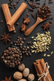Photo of Different spices on black textured table, flat lay