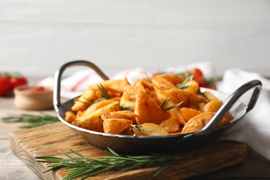 Photo of Metal dish with baked potatoes and rosemary on table