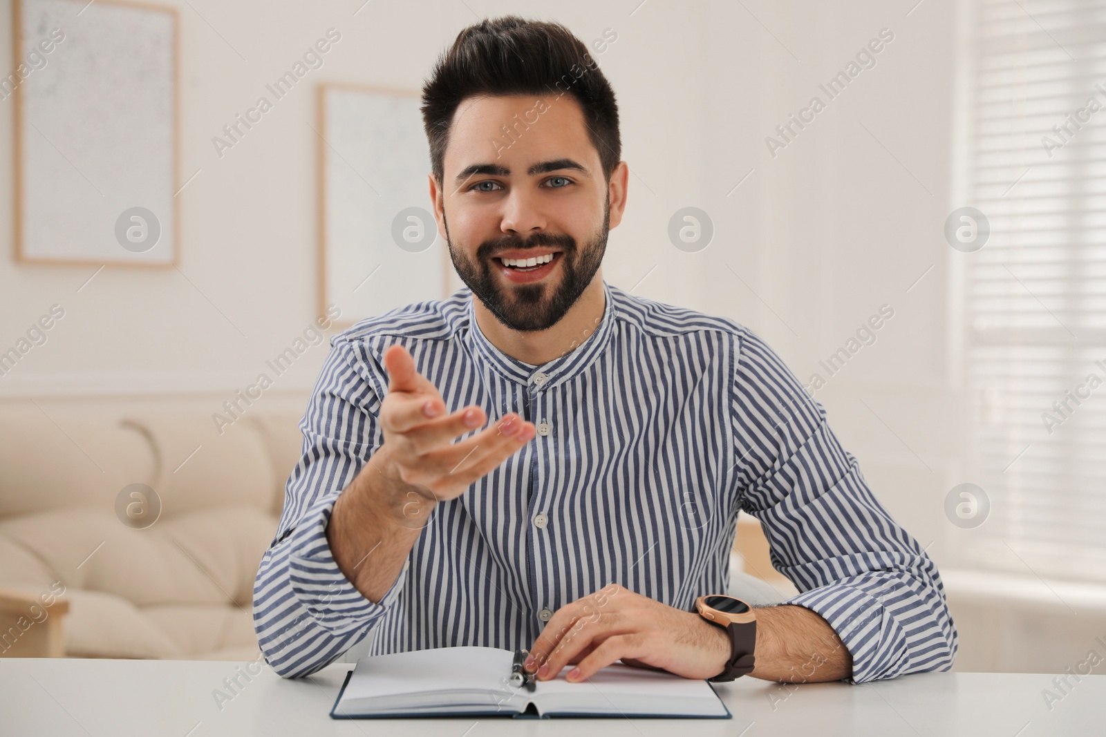 Photo of Young man conducting webinar at desk in room