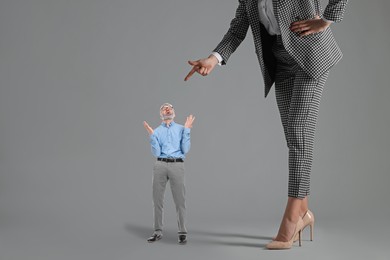 Giant woman pointing at small man on grey background