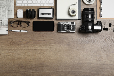 Flat lay composition with equipment for journalist on wooden table. Space for text