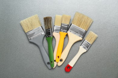 Photo of Many different paint brushes on grey background, flat lay