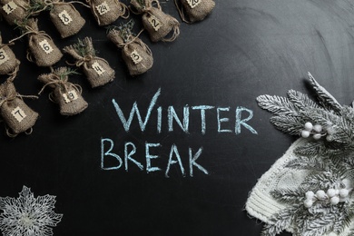 Flat lay composition of Christmas decorations and advent calendar on school blackboard with phrase Winter Break