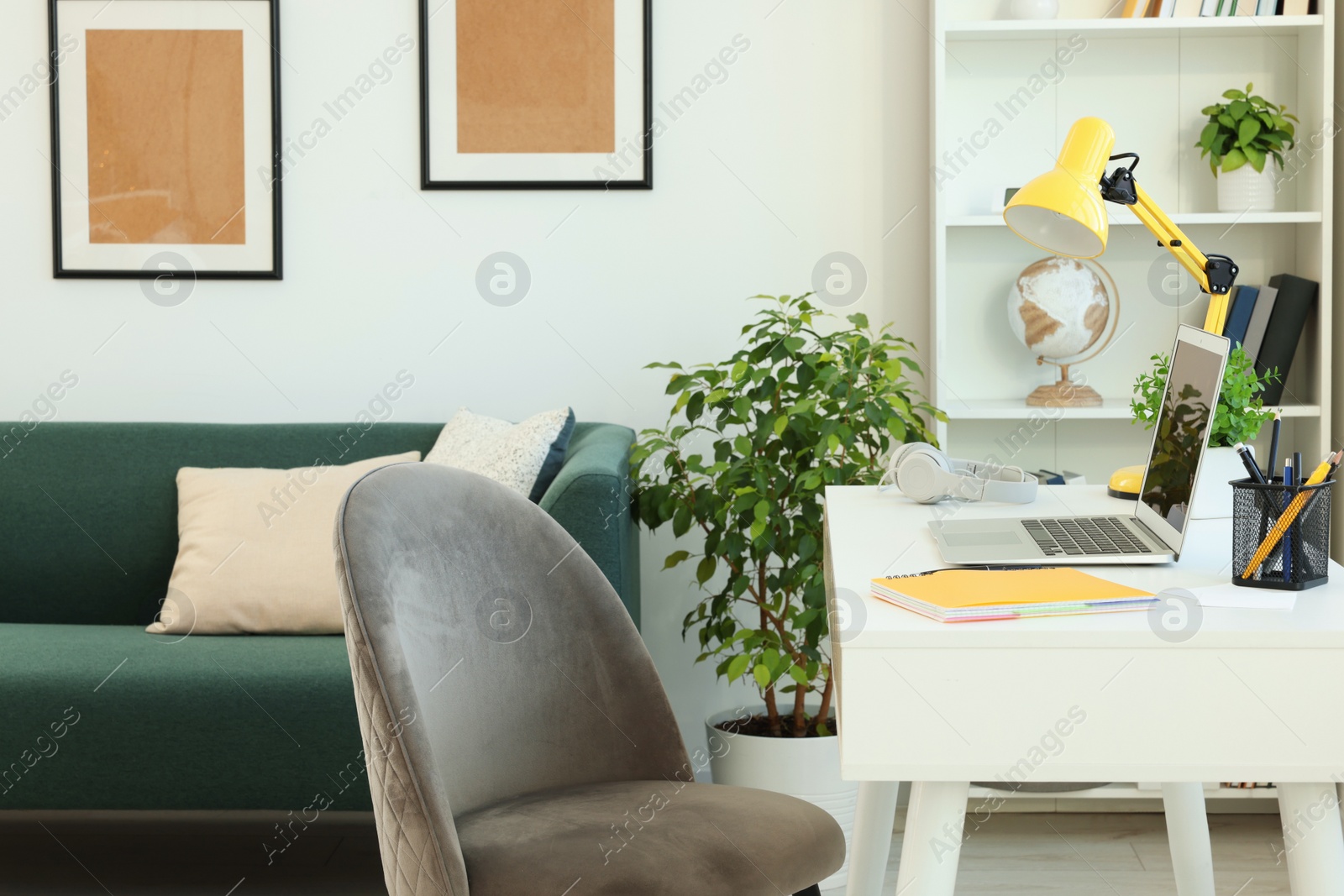 Photo of Cozy workspace with modern laptop on white wooden desk and comfortable chair at home