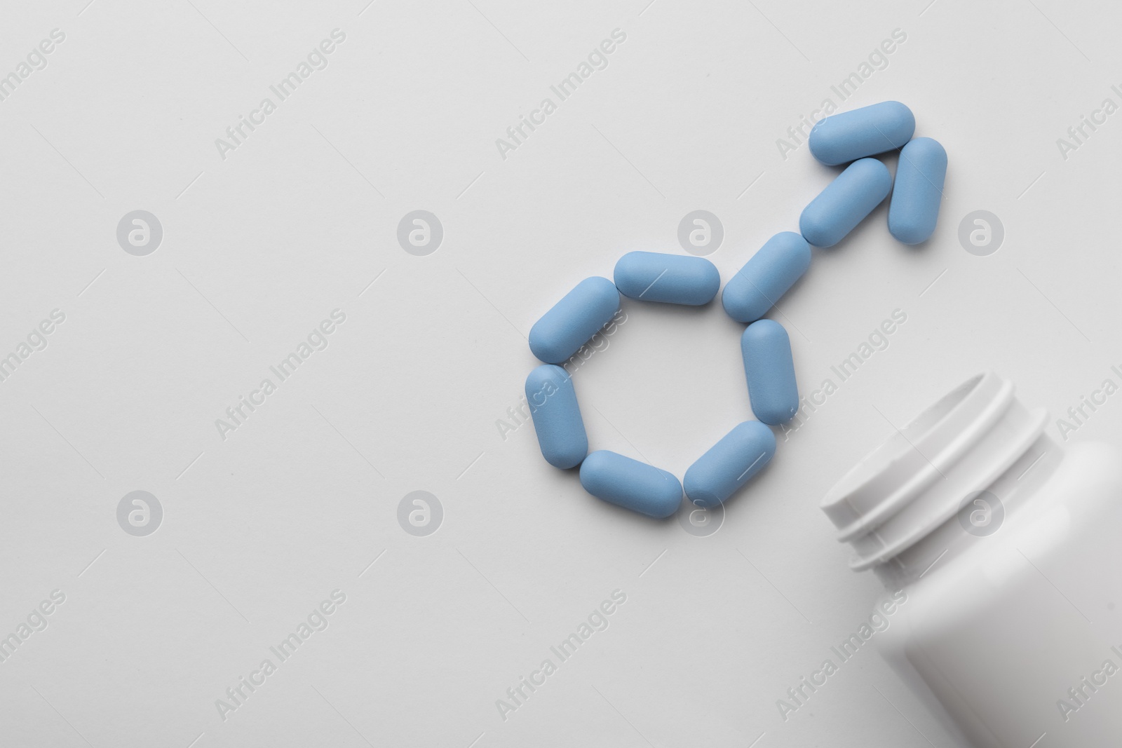 Photo of Male sign made of pills and medical bottle on white background, top view with space for text. Potency problem