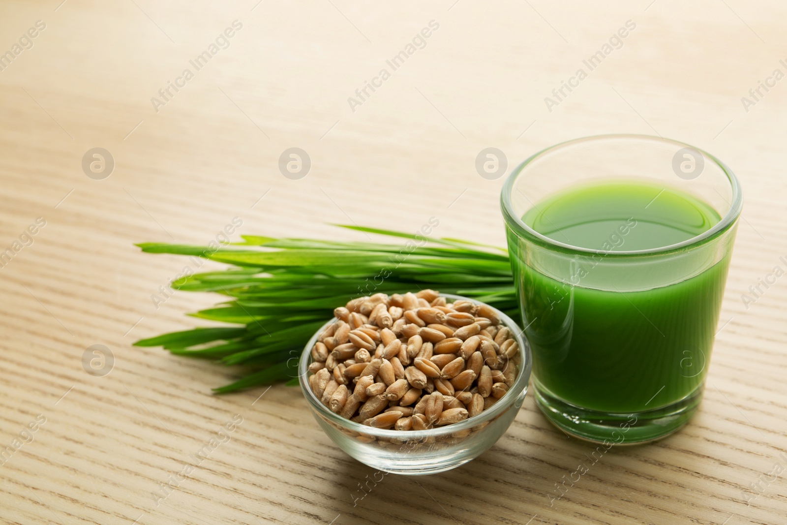 Shot glass of wheat grass juice, bowl with grains and sprouts on wooden table Photo of Shot glass of wheat grass juice, bowl with grains and sprouts on wooden table