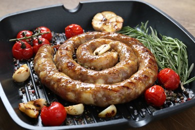 Pan with delicious homemade sausage, garlic, tomatoes, rosemary and spices on table, closeup
