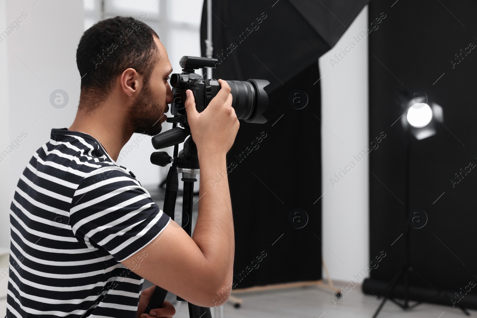 Photo of Young professional photographer taking picture in modern photo studio, space for text