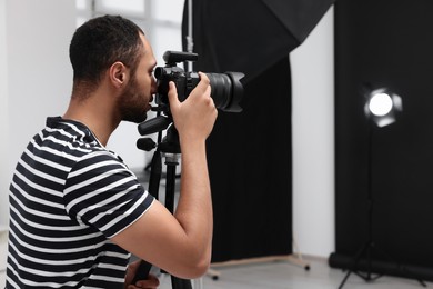 Young professional photographer taking picture in modern photo studio, space for text