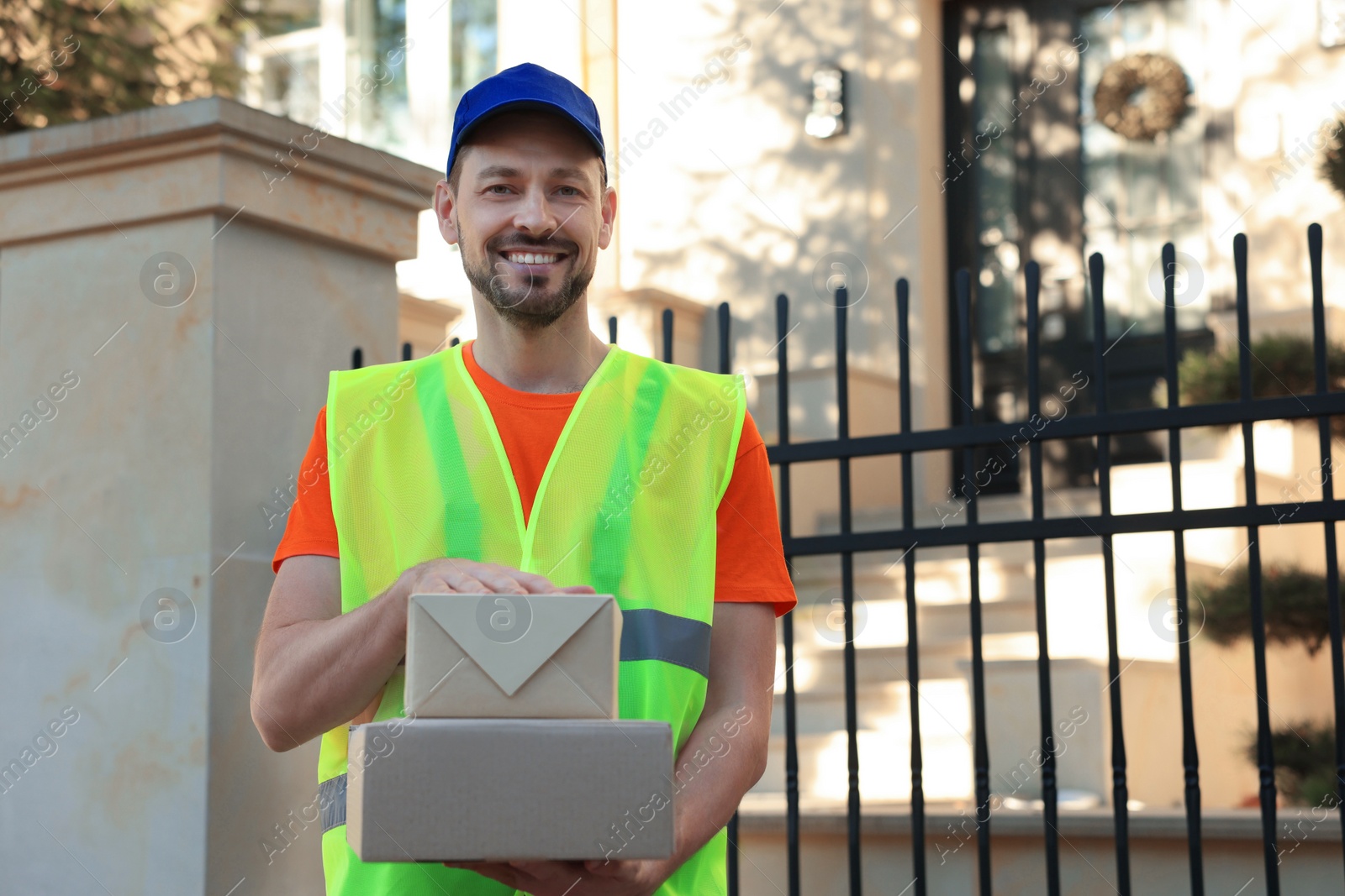 Photo of Courier in uniform with two parcels outdoors