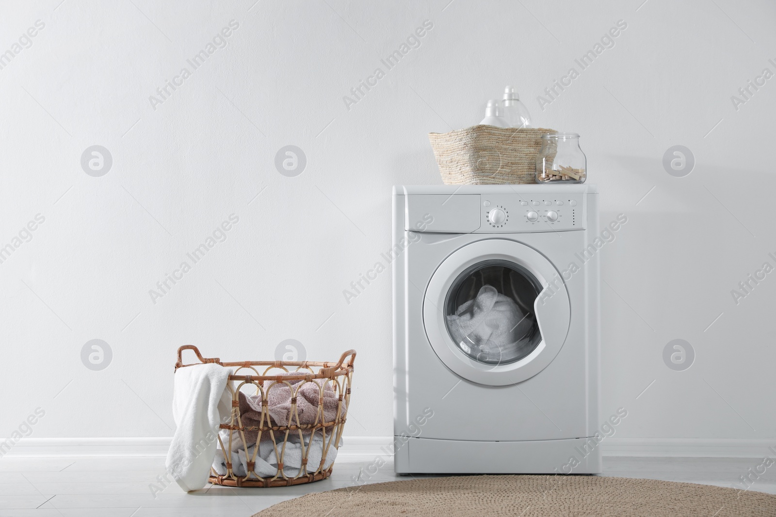 Photo of Modern washing machine and laundry baskets near white wall indoors. Bathroom interior