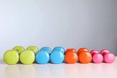 Photo of Many dumbbells for on table against color background. Fitness equipment