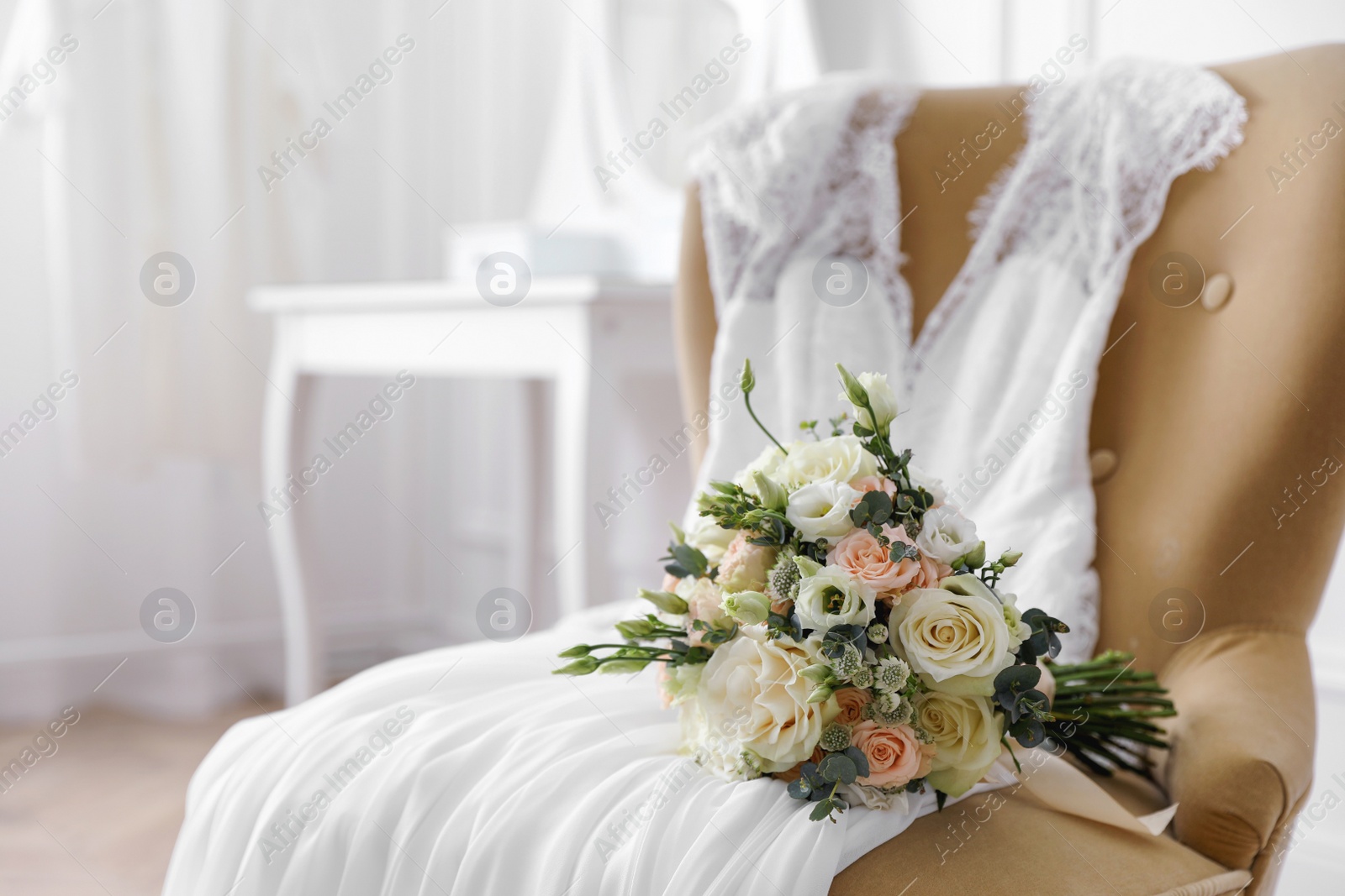 Photo of Beautiful wedding bouquet and dress on armchair indoors