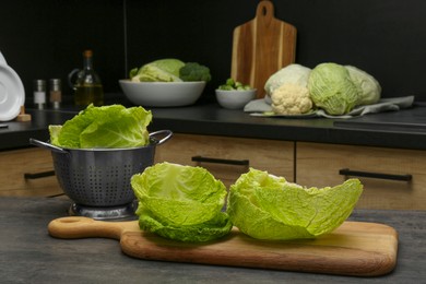 Photo of Fresh Savoy cabbage leaves on black table in kitchen