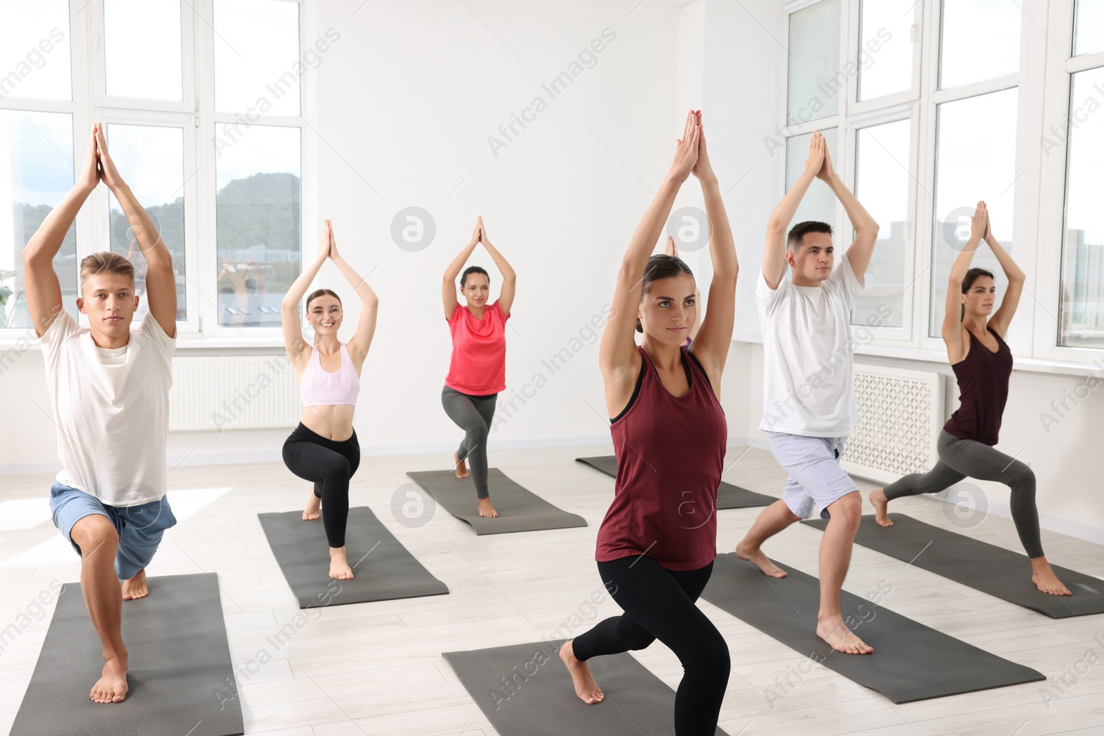 Photo of Group of people practicing yoga on mats indoors