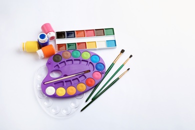 Photo of Set of paints and brushes on white background, top view. Artistic equipment for children