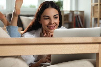 Young woman working with laptop on sofa at home