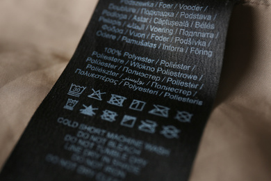 Photo of Clothing label with care symbols and material content on shirt, closeup view