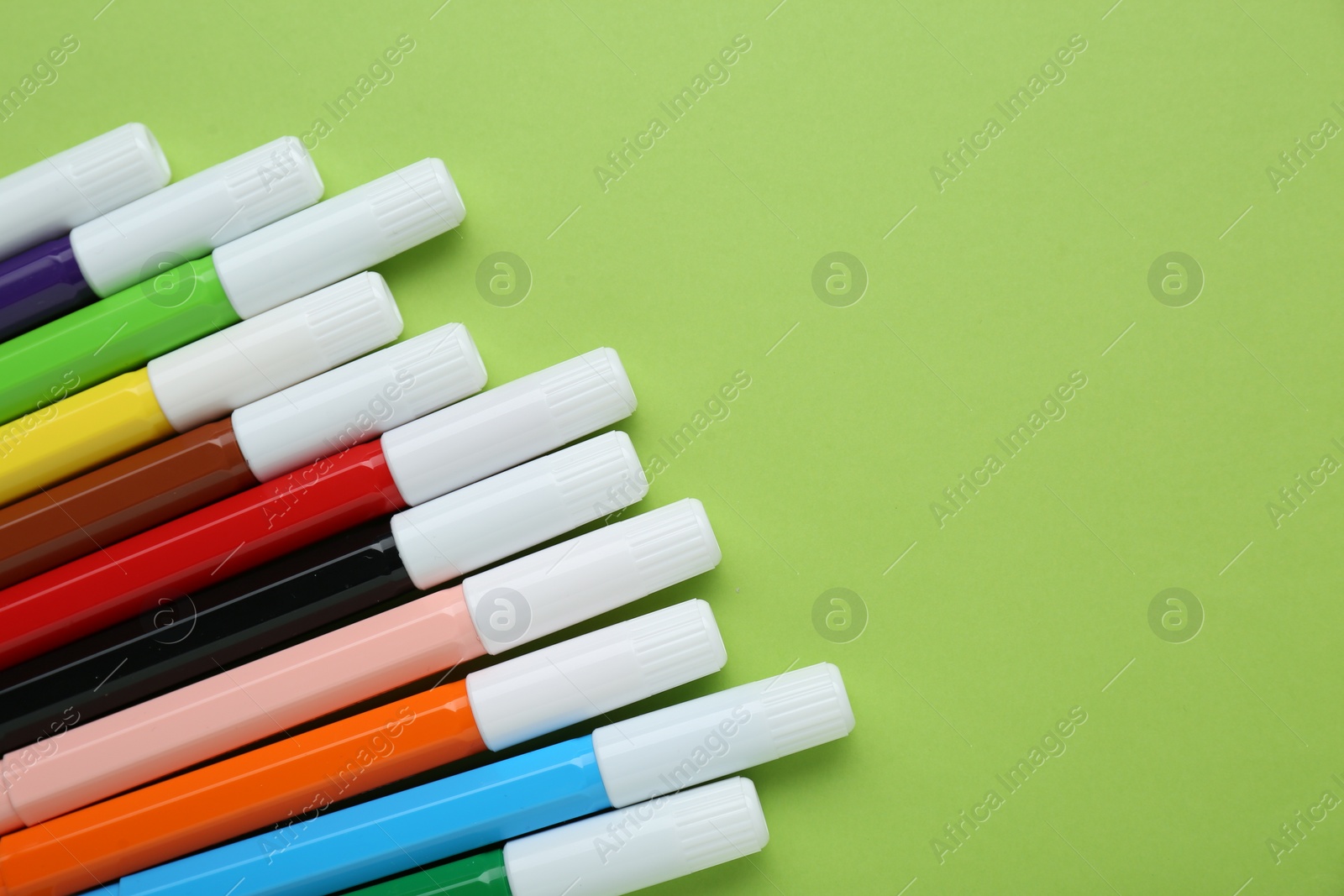 Photo of Many different colorful markers on light green background, flat lay. Space for text