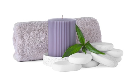 Photo of Composition with towel, candle and spa stones isolated on white