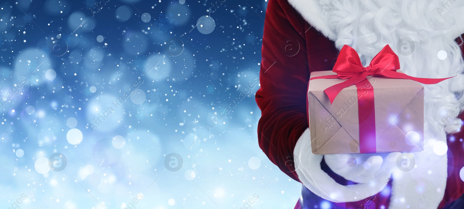 Image of Santa Claus holding gift box on winter background, bokeh effect. Space for text