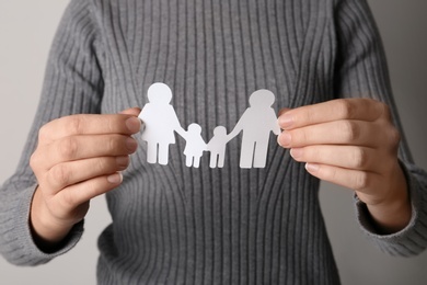 Woman holding paper silhouette of family, closeup. Life insurance concept