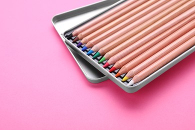 Photo of Box with many colorful pastel pencils on pink background, closeup and space for text. Drawing supplies