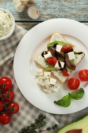 Photo of Delicious sandwich with anchovies, cheese, tomatoes and sauce on wooden table, flat lay