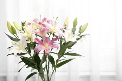 Photo of Vase with bouquet of beautiful lilies on blurred background. Space for text