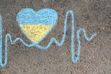 Photo of Cardiogram line with heart drawn by blue and yellow chalk on asphalt, top view