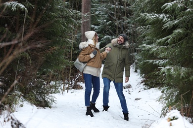 Photo of Couple in conifer forest on snowy day. Winter vacation