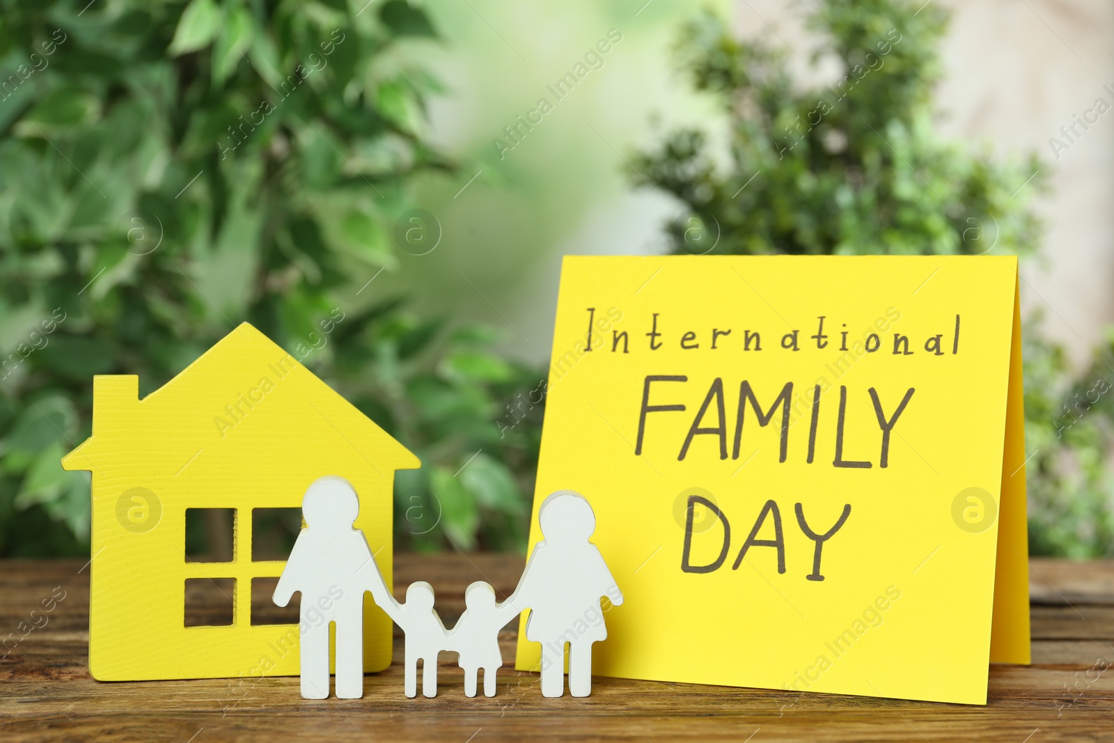 Photo of Card with text International Family Day and figures on wooden table