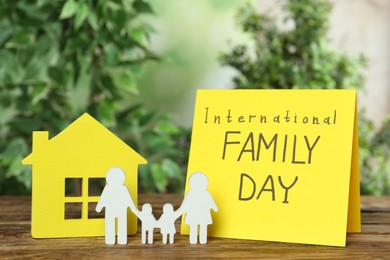 Photo of Card with text International Family Day and figures on wooden table