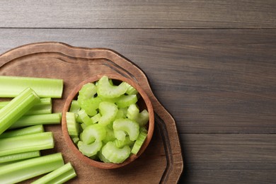 Photo of Board with fresh cut and whole celery on wooden table, top view. Space for text