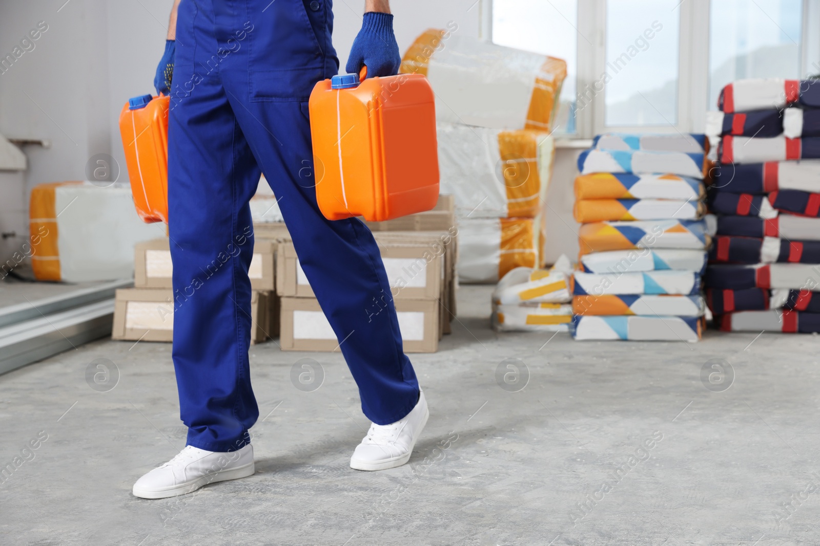 Photo of Construction worker carrying canisters in room prepared for renovation, closeup