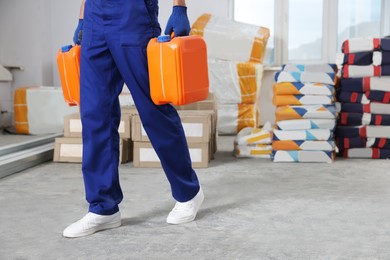 Construction worker carrying canisters in room prepared for renovation, closeup