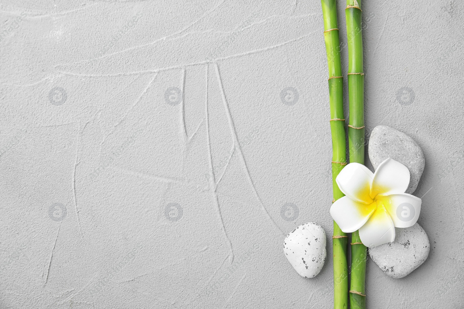 Photo of Composition with bamboo branches, stones and plumeria on light background, top view. Space for text