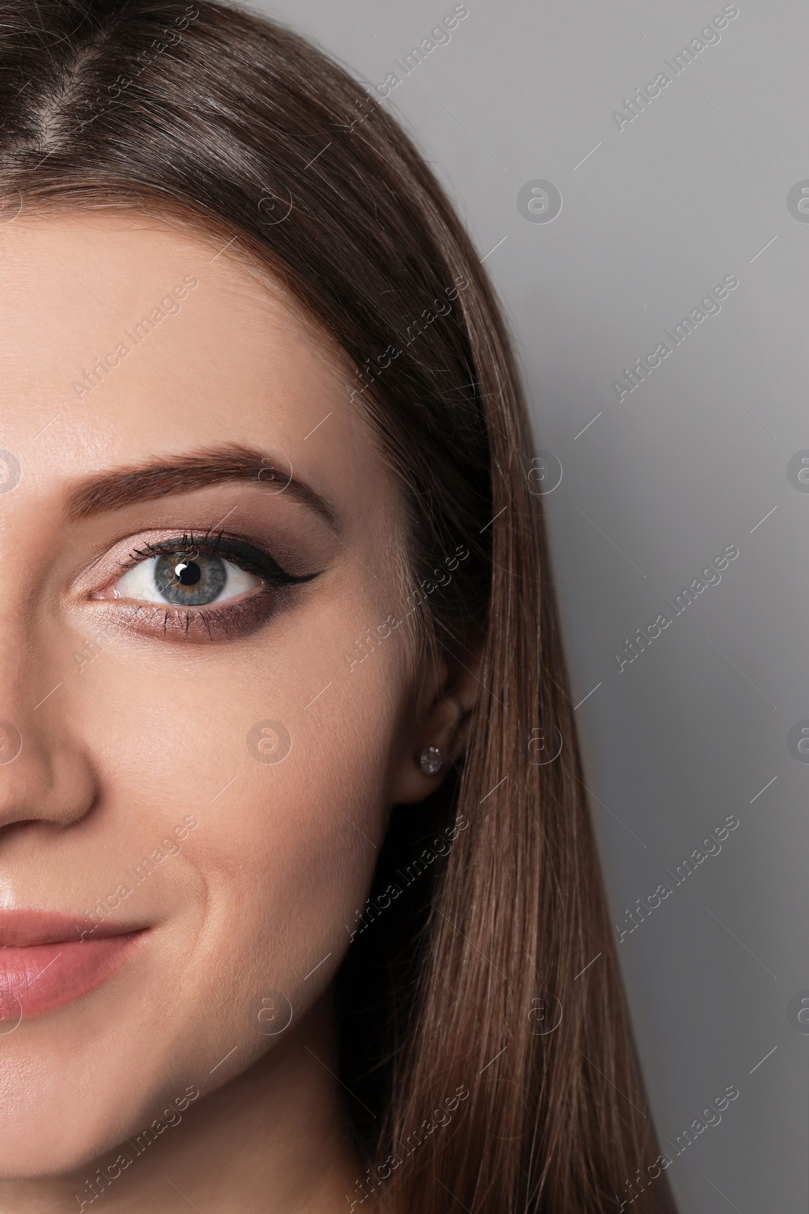Photo of Beautiful woman with black eyeliner on grey background, closeup