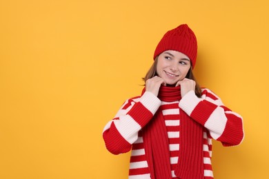 Beautiful woman in warm scarf on yellow background, space for text