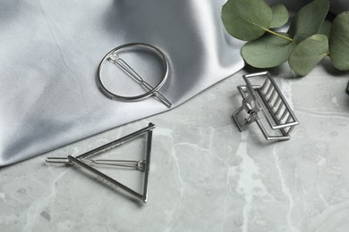 Photo of Stylish hair clips and fabric on grey marble table