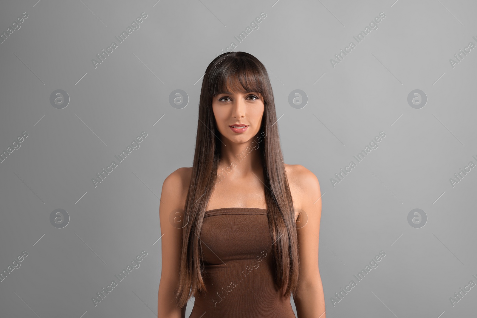 Photo of Hair styling. Portrait of beautiful woman with straight long hair on grey background