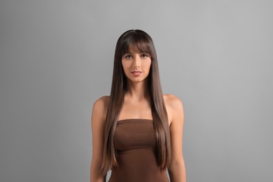 Photo of Hair styling. Portrait of beautiful woman with straight long hair on grey background