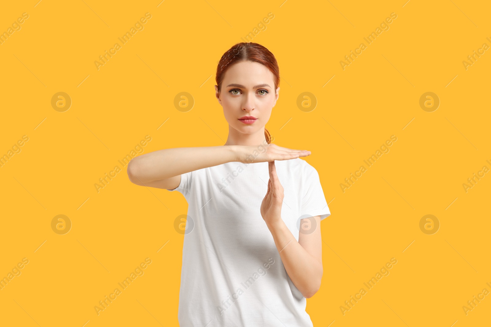 Photo of Woman showing time out gesture on yellow background