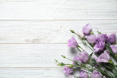 Beautiful fresh Eustoma flowers on white wooden table, flat lay. Space for text