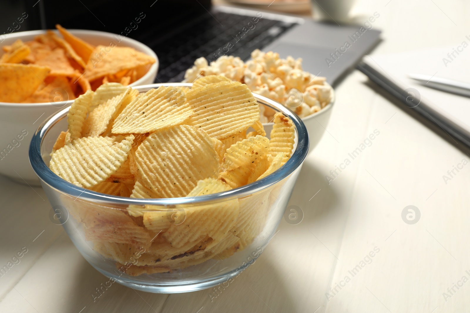 Photo of Bad eating habits at workplace. Different snacks on white wooden table, space for text