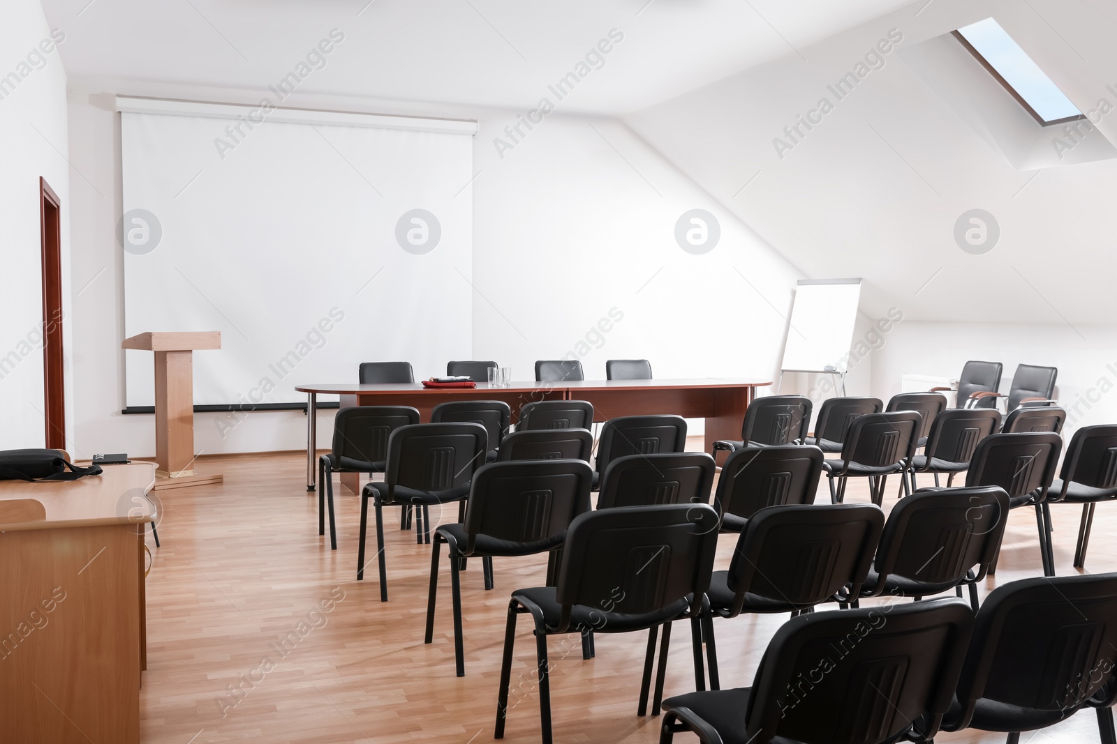 Photo of Empty conference room with projection screen, wooden table and many chairs